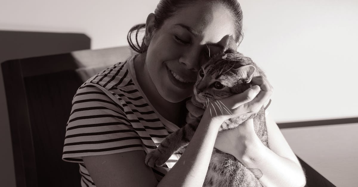 A woman lovingly embraces her cat, showcasing a tender moment indoors.